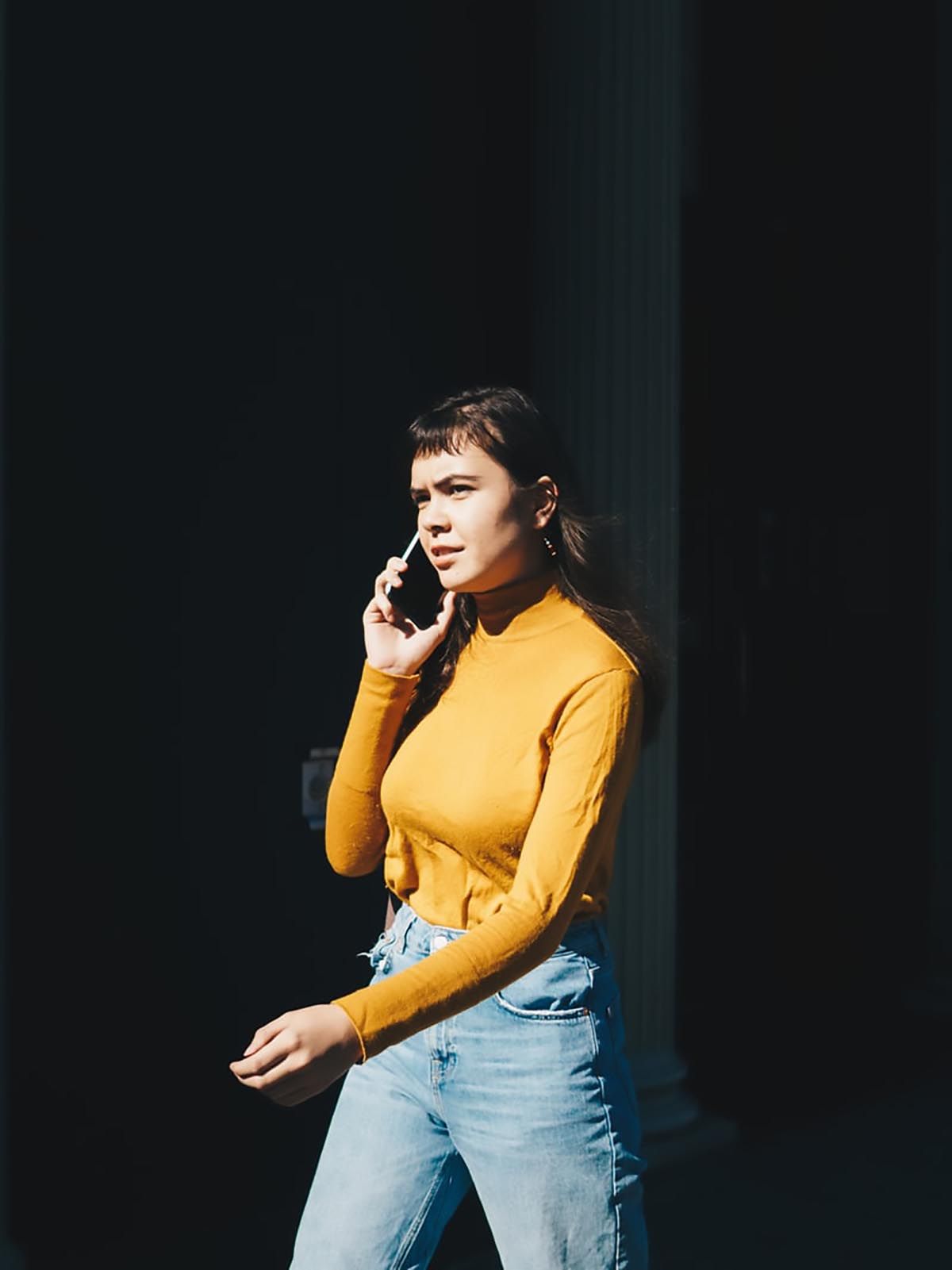 kvinna i gul tröja som pratar i telefon